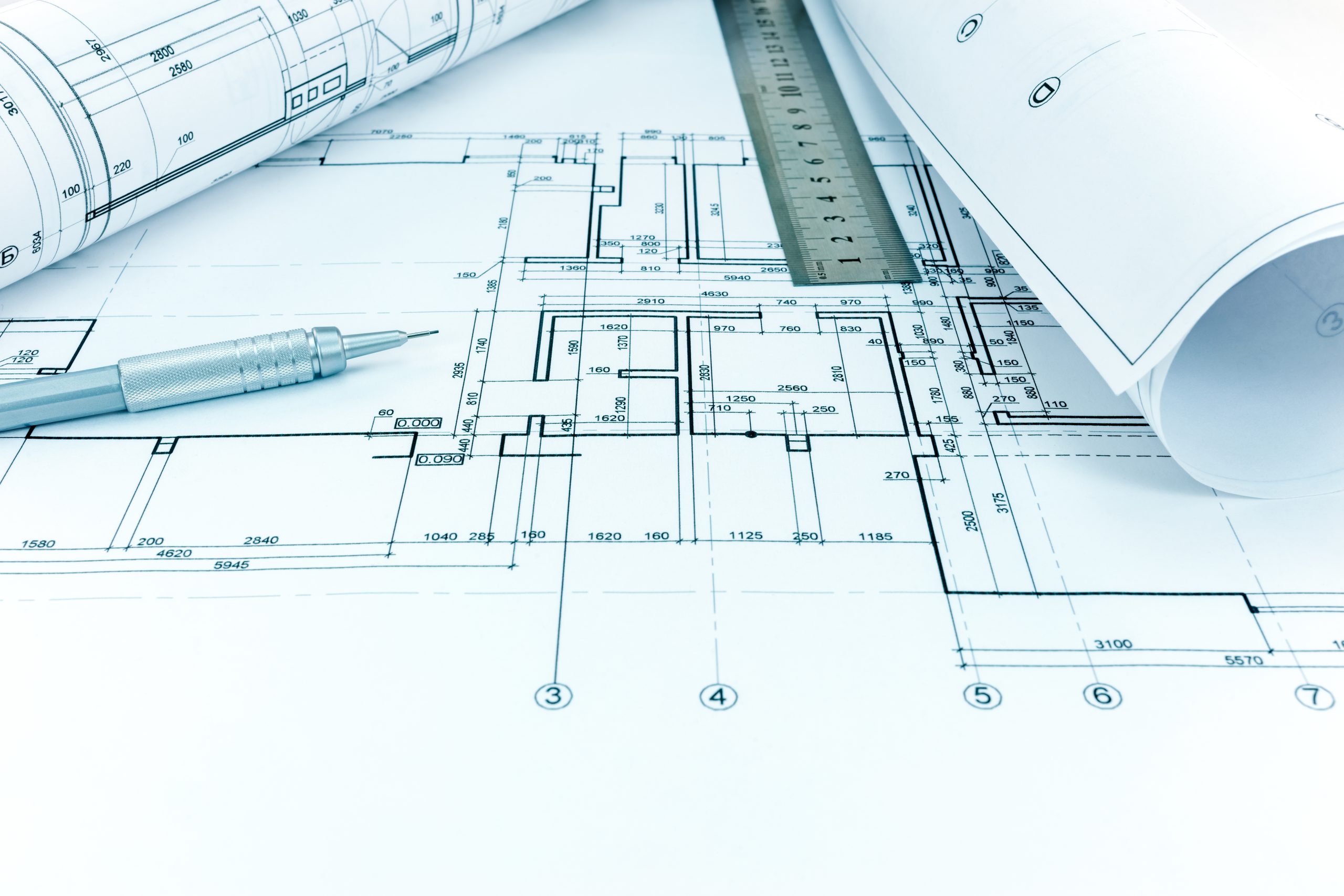 rolled blueprints, ruler and mechanic pencil on graphical architectural plan of flat